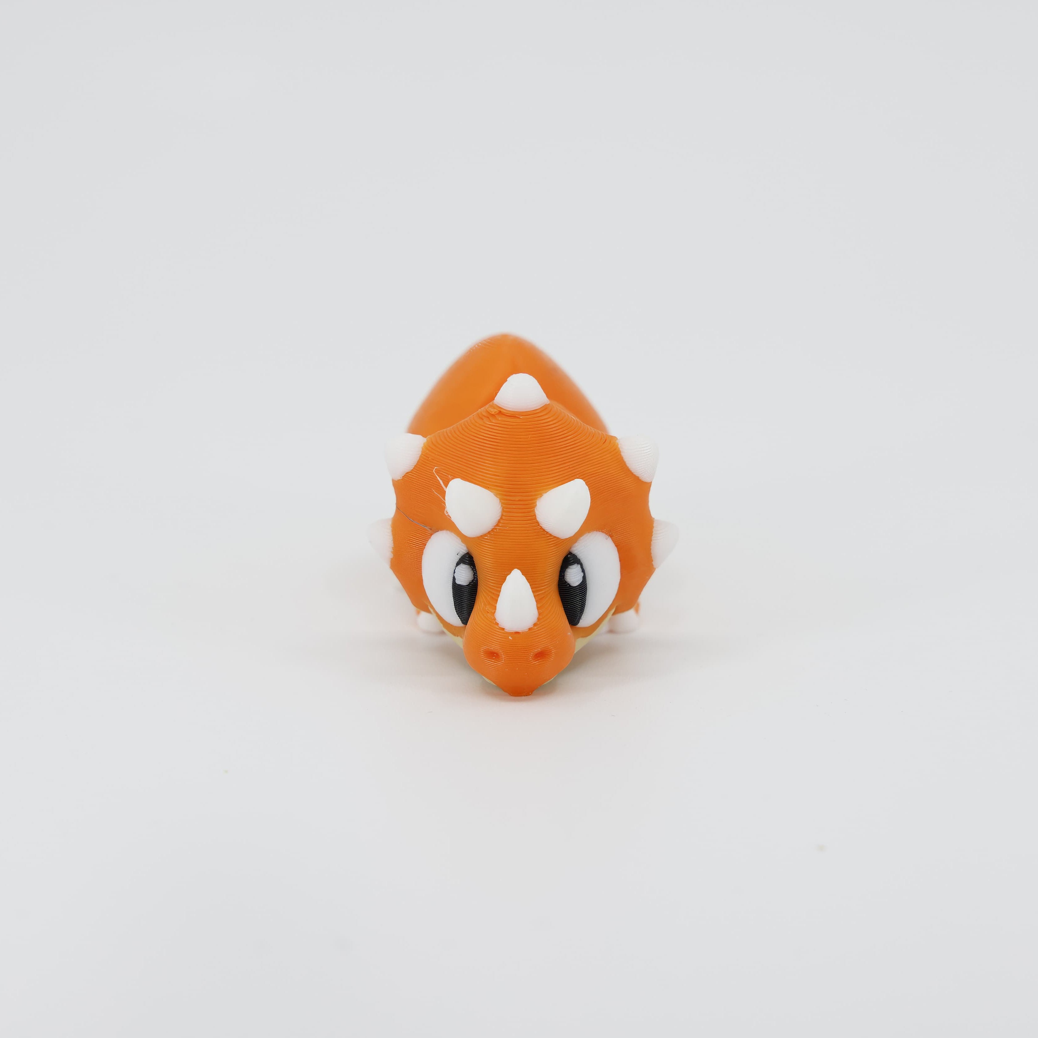 3D printed Triceratops Wiggle Bud flexible toy shown from the front. Highlights the iconic large frill and three horns, a sturdy articulated dinosaur model.