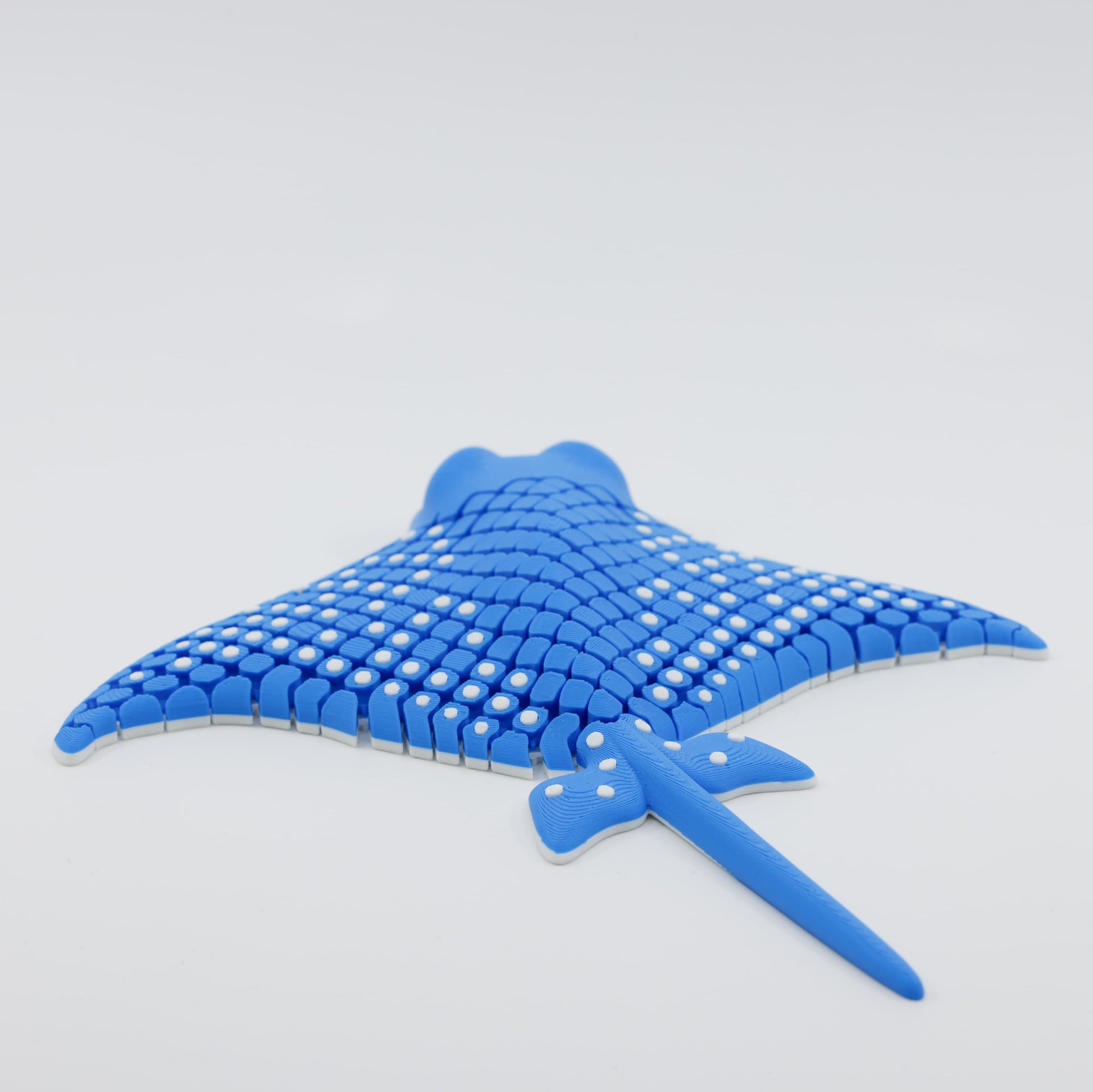 Back view of 3D printed flexible stingray fidget highlighting its articulated fins and textured surface in blue