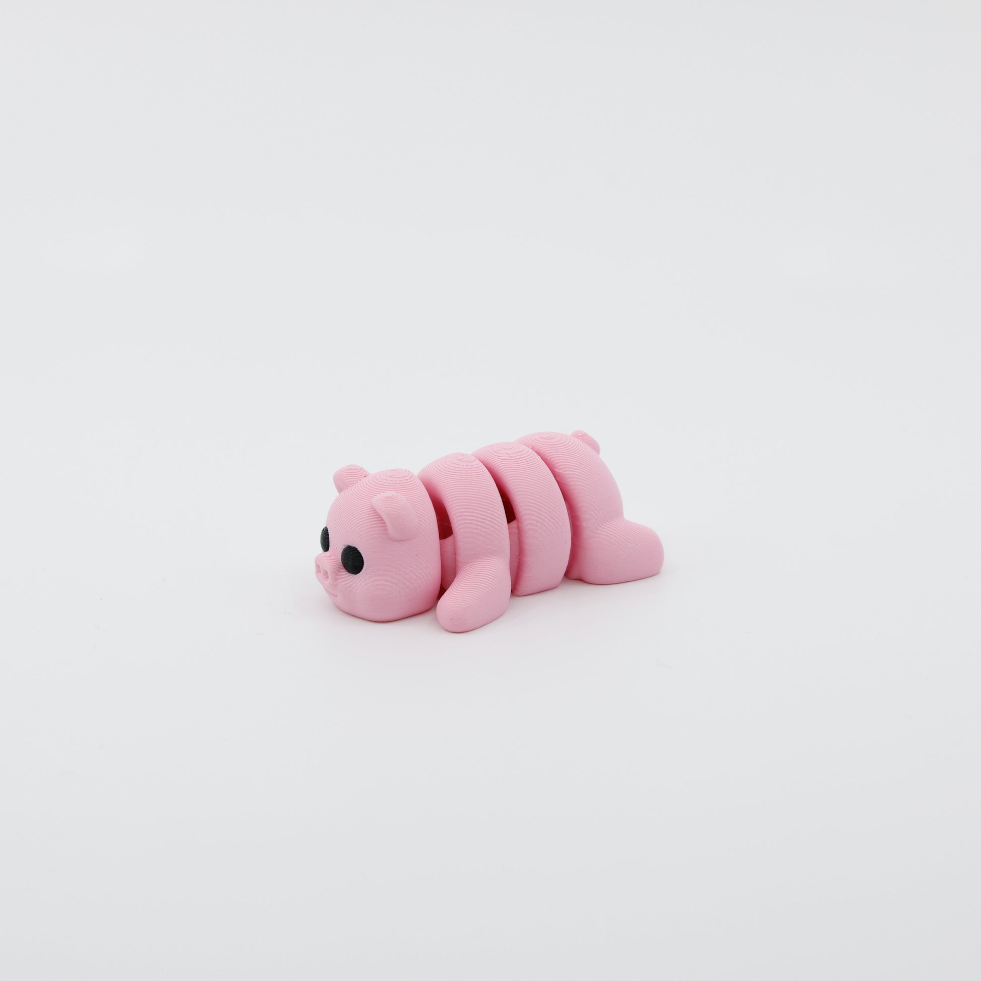 Side profile of articulated pig sensory fidget highlighting smooth body segments and adorable features