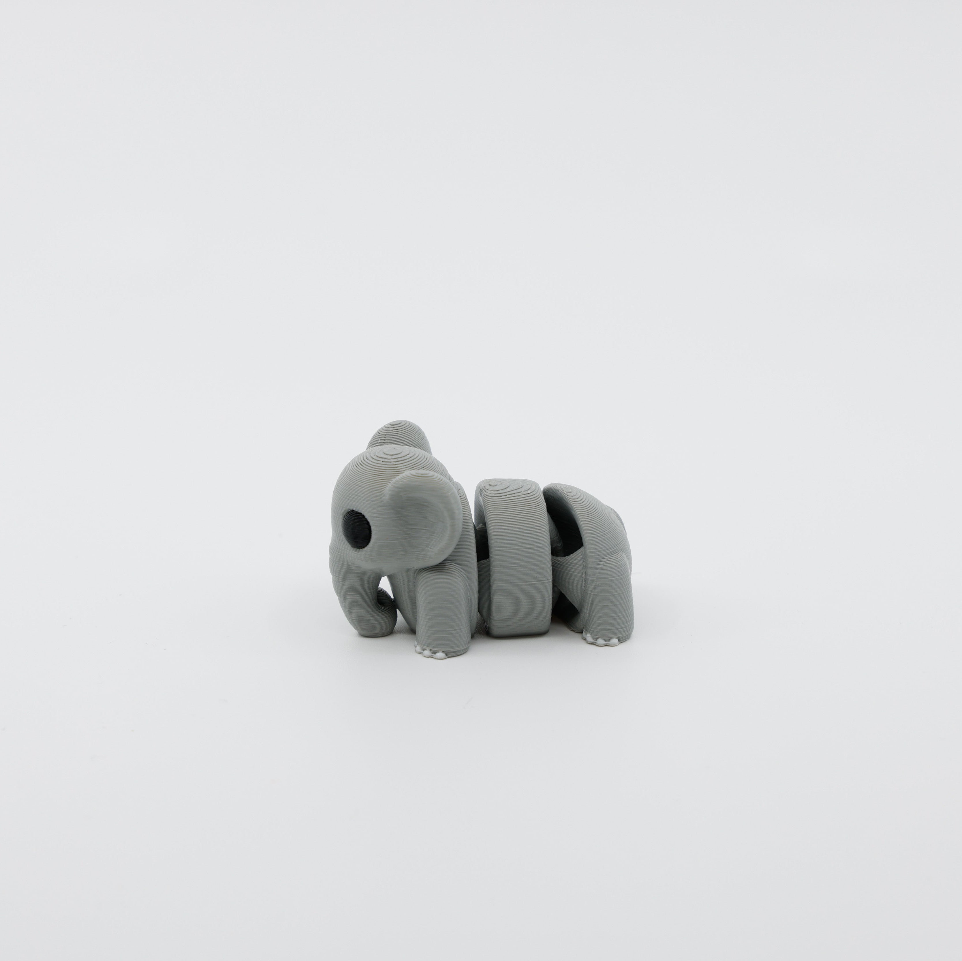 Side profile of articulated elephant sensory fidget highlighting curved body segments and trunk design