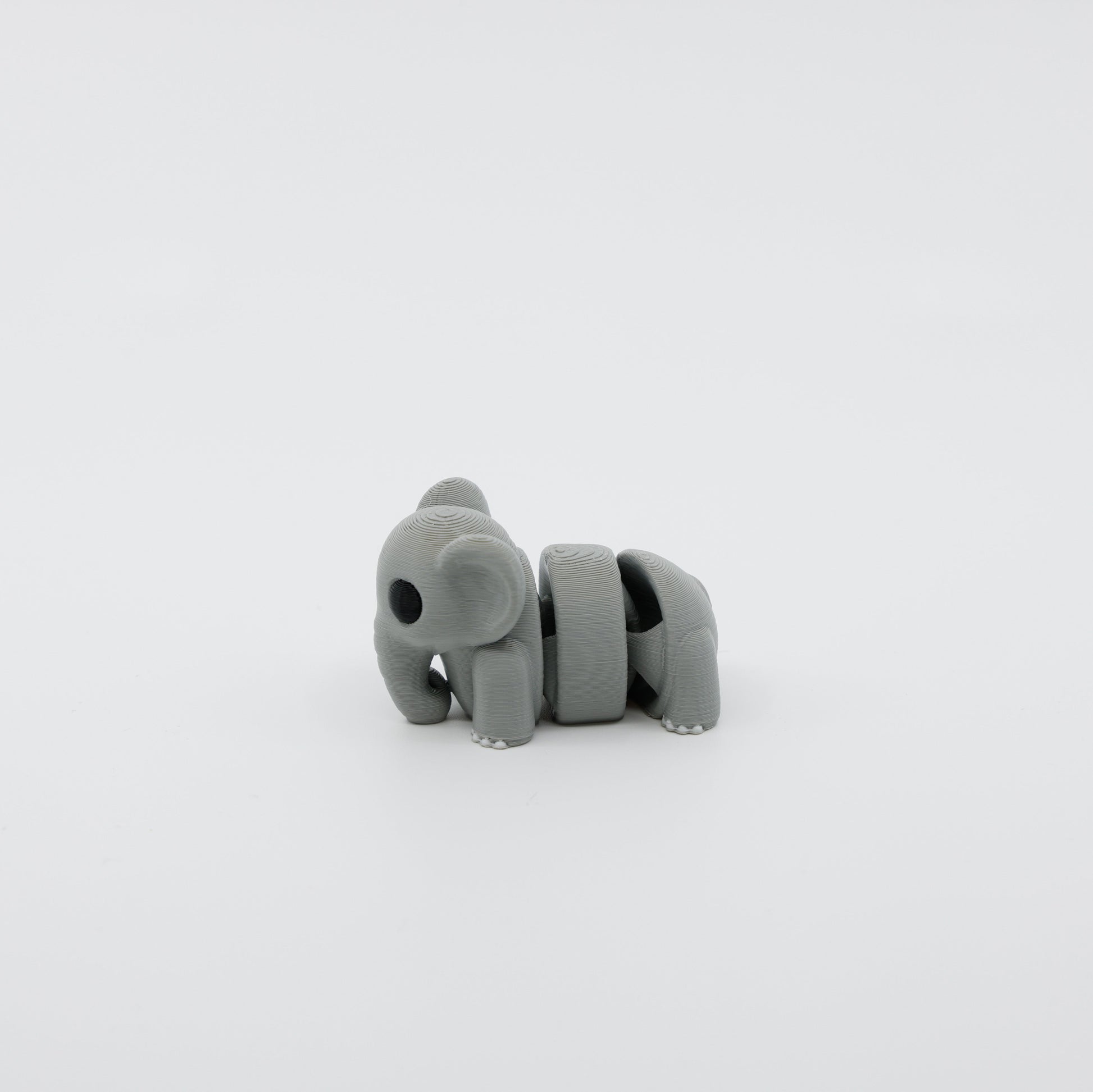 Side profile of articulated elephant sensory fidget highlighting curved body segments and trunk design