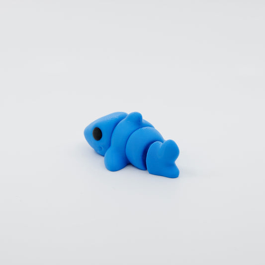 Side profile of articulated shark sensory fidget highlighting flowing body segments and dorsal fin