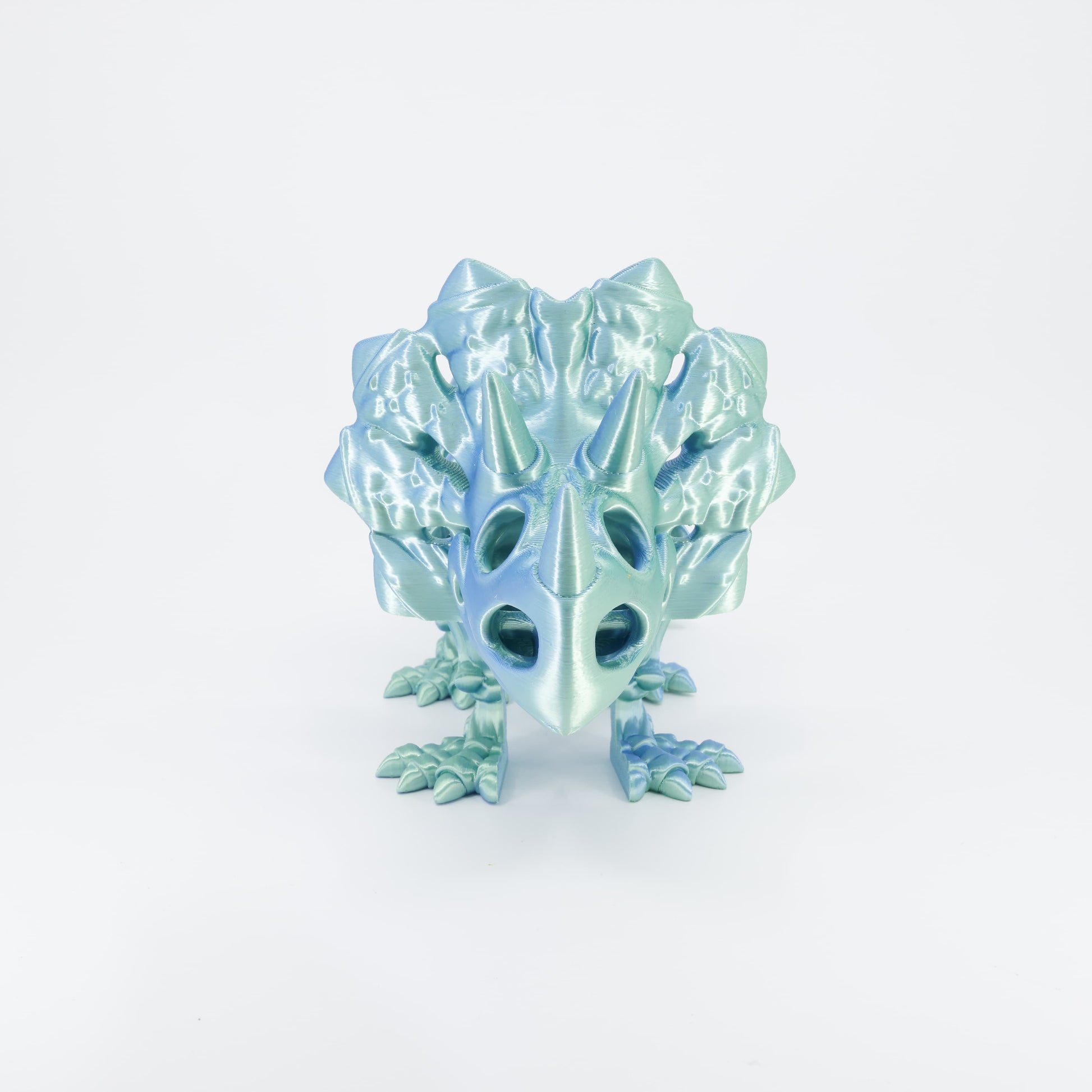 Flexi 3D printed dinosaur skeleton Triceratops shown from the front. Highlights the large frill, three horns, and articulated legs.