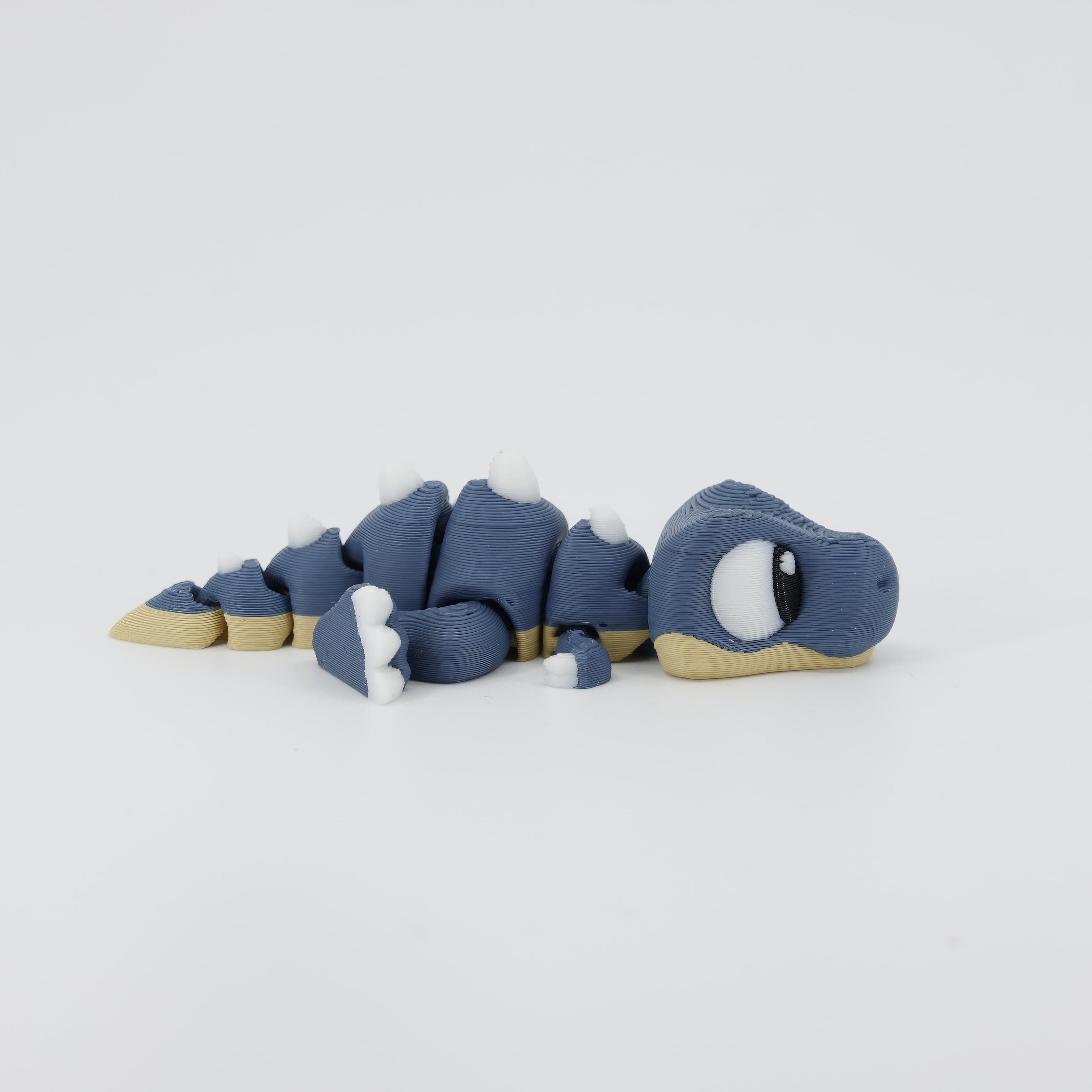 Side view detail of the flexible 3D printed T-Rex Wiggle Bud. Shows the articulated body segments that allow the toy to move and wiggle.