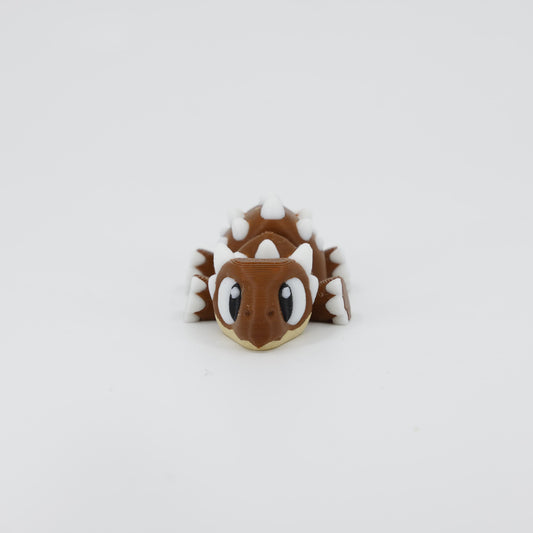Front view of the Mini Ankylosaurus Wiggle Bud fidget toy. Highlights the wide armoured head and articulated legs created via 3D printing.