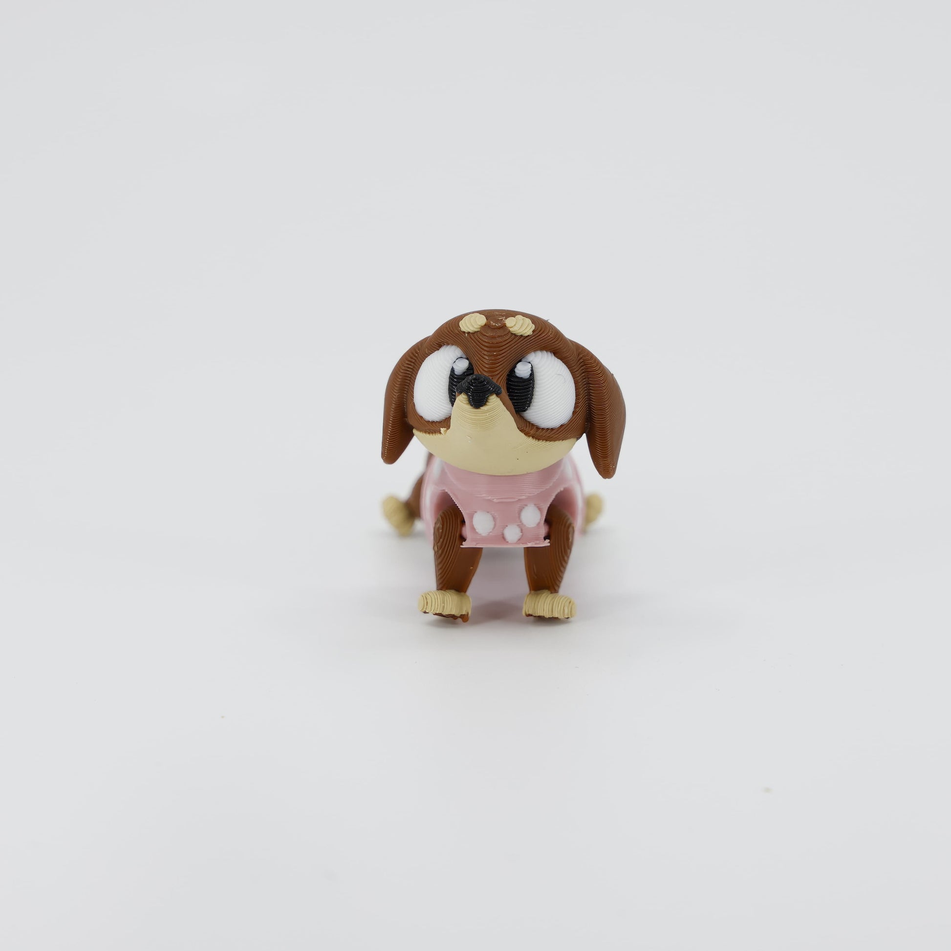 Front view of the Mini Sausage Dog Wiggle Bud fidget toy. Highlights the cute floppy ears and short articulated legs created via 3D printing.