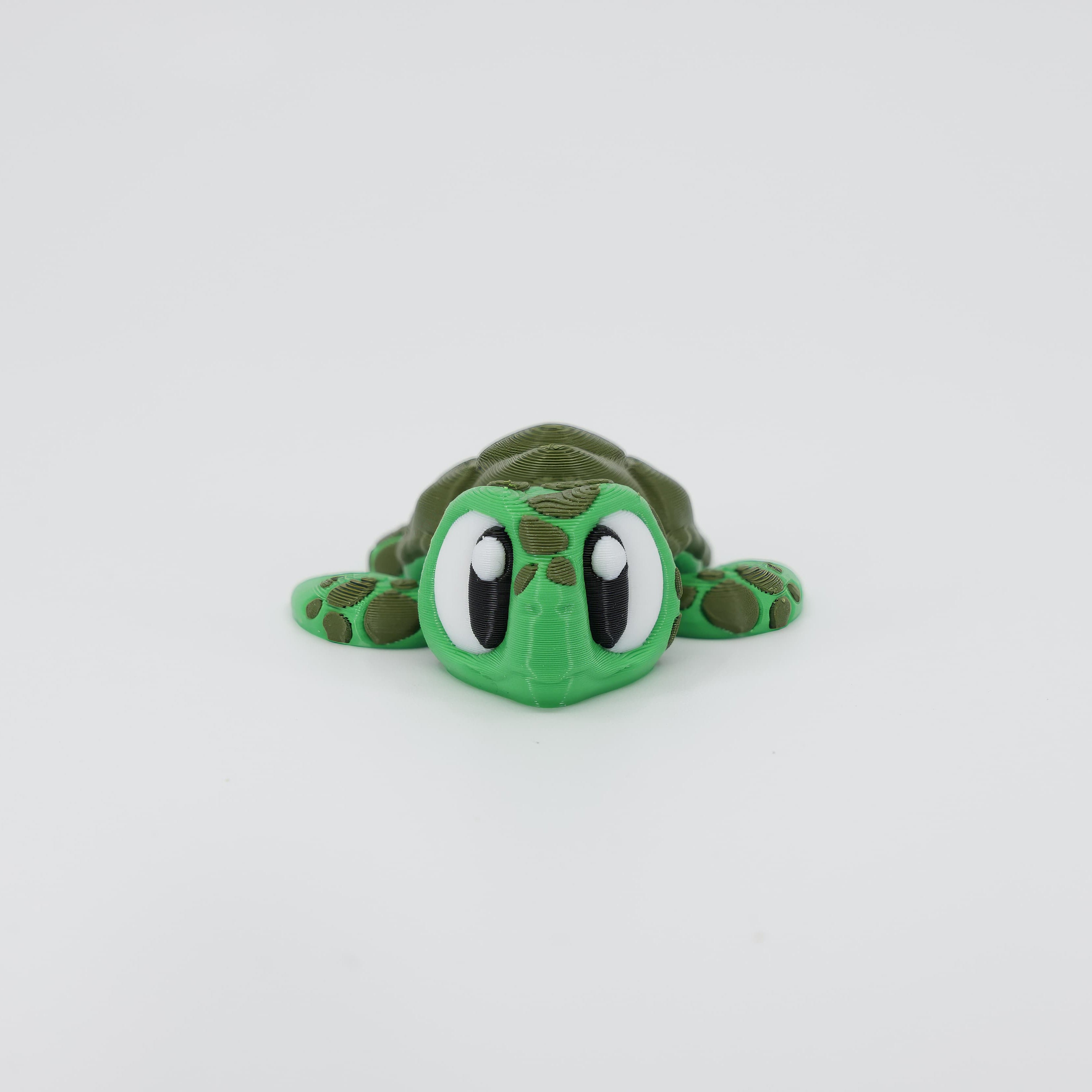 Front view of the Mini Sea Turtle Wiggle Bud fidget toy. Highlights the cute head and articulated flippers created via 3D printing.