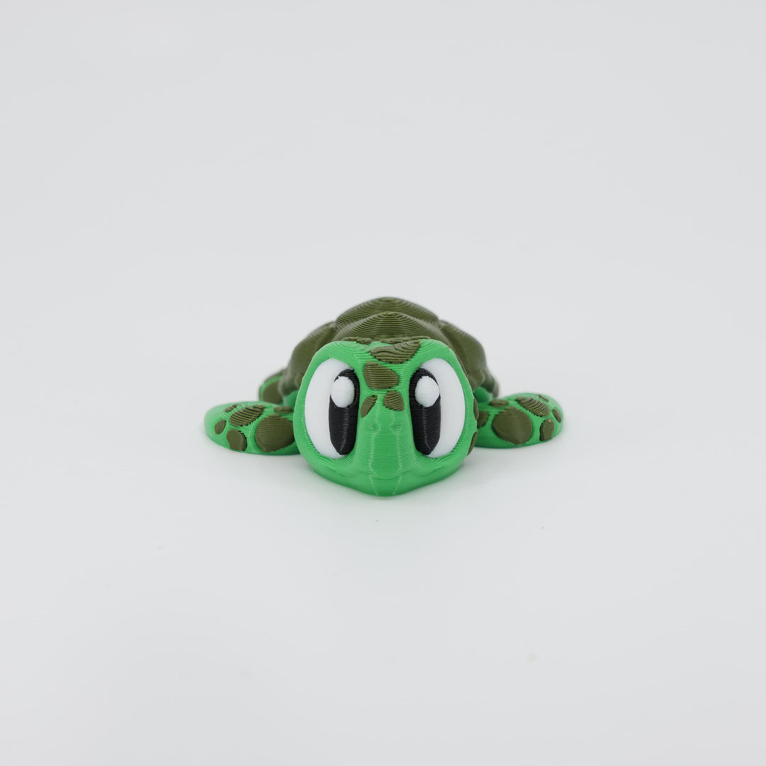 Front view of the Mini Sea Turtle Wiggle Bud fidget toy. Highlights the cute head and articulated flippers created via 3D printing.