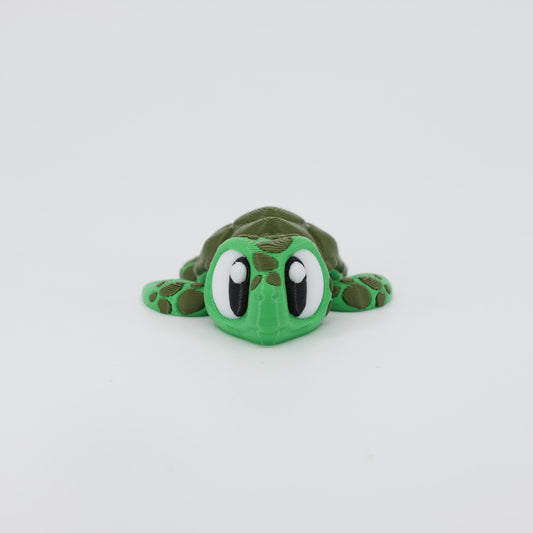 Front view of the Mini Sea Turtle Wiggle Bud fidget toy. Highlights the cute head and articulated flippers created via 3D printing.