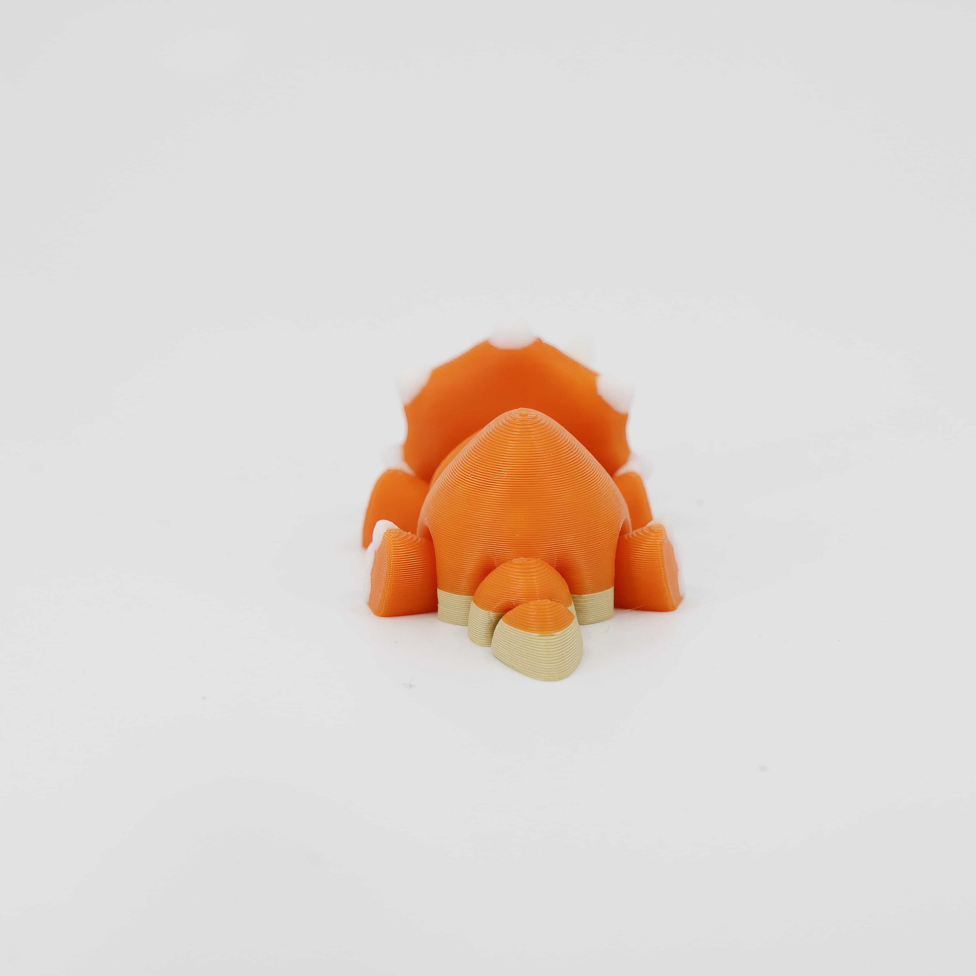Back view of the miniature 3D printed Triceratops Wiggle Bud toy. Clearly shows the rear of the frill and the segmented tail that enables the flexible dinosaur toy's movement.