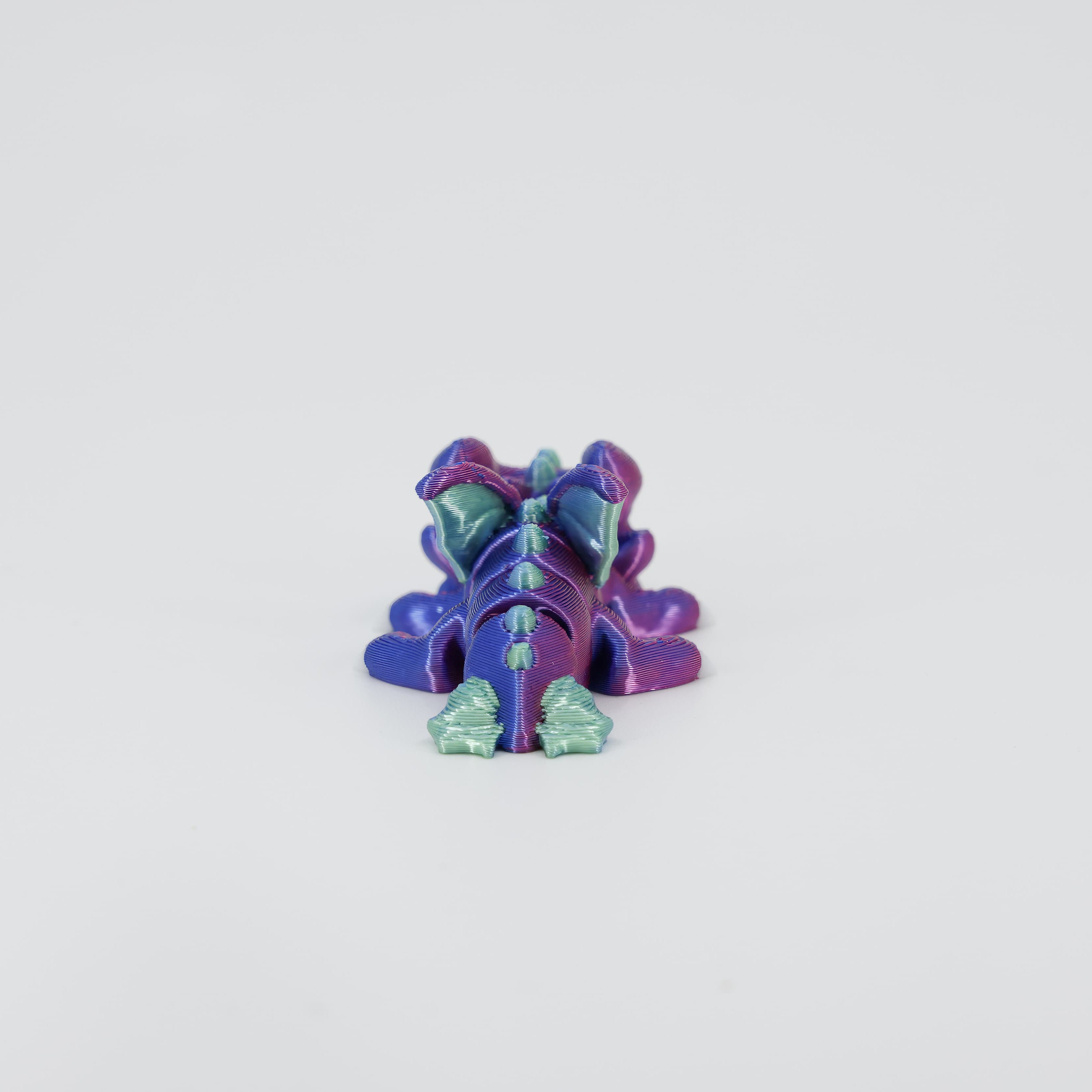 Back detail of the sensory 3D printed mini dragon, emphasising the segmented tail designed for satisfying wiggle movement