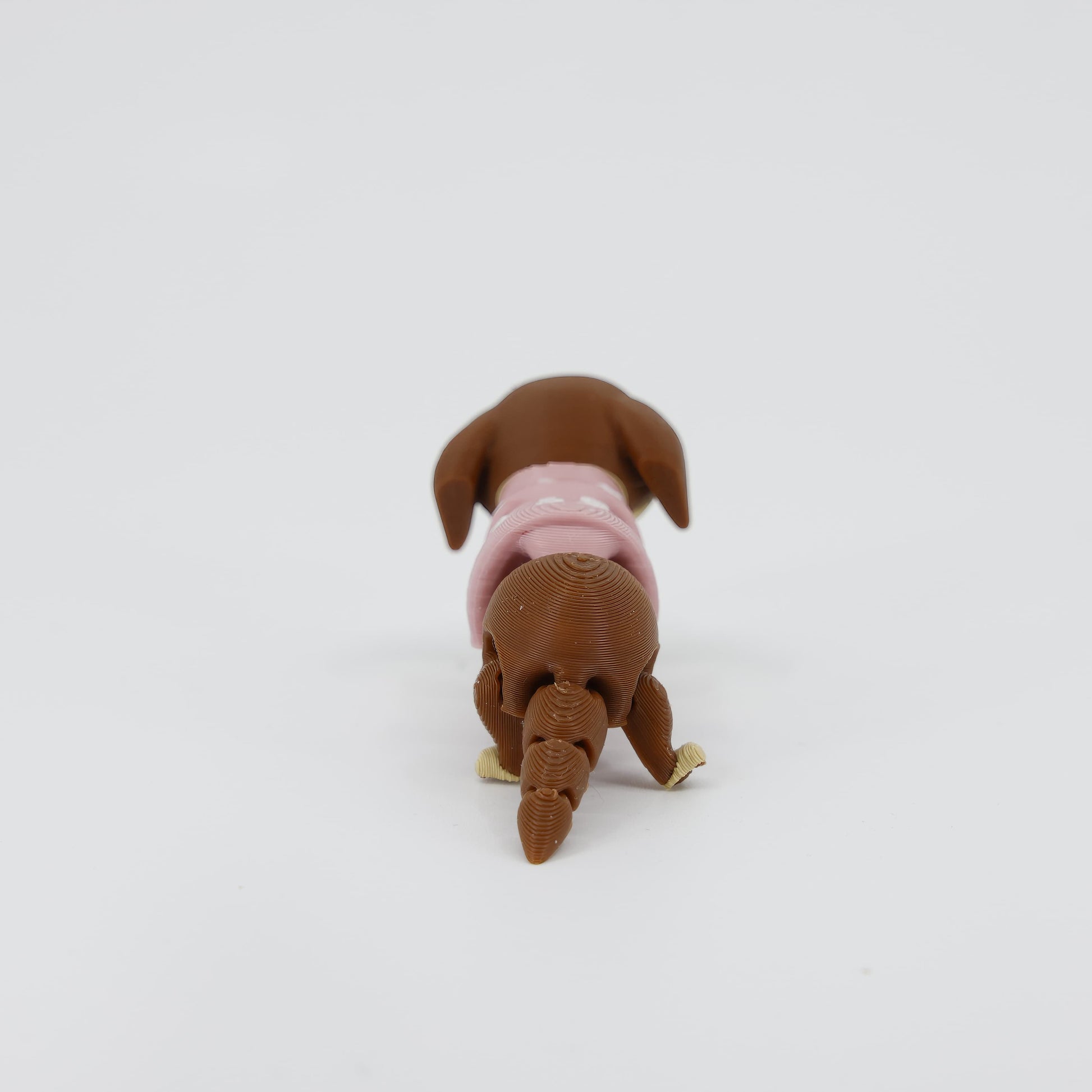 Back detail of the sensory 3D printed mini sausage dog, emphasizing the smooth texture and wagging tail designed for fidget play.