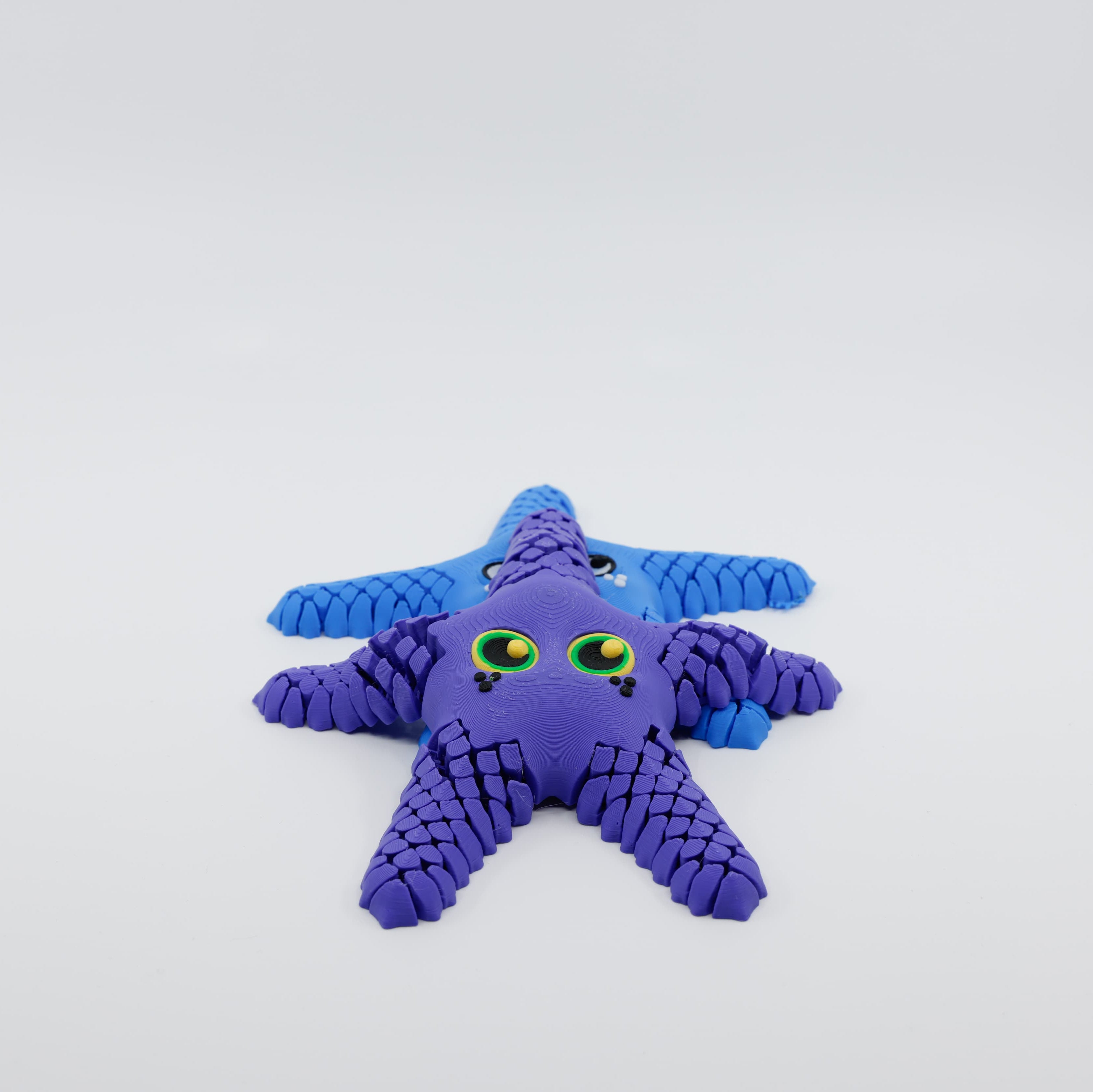 Front view of 3D printed flexi starfish fidget with articulated arms purple on top of blue